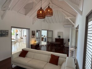 Un salón amplio con un sofá blanco, una mesa de comedor y una cocina al fondo.