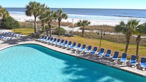 Ein Pool mit blauen Stühlen und Blick auf den Strand.