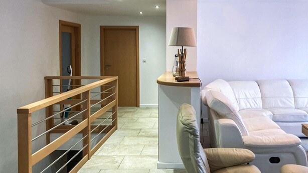 A modern interior with a wooden staircase, a white sofa, and a lamp on a small table. - 3 bedroom amazing home in Mutigney (Mutigney)