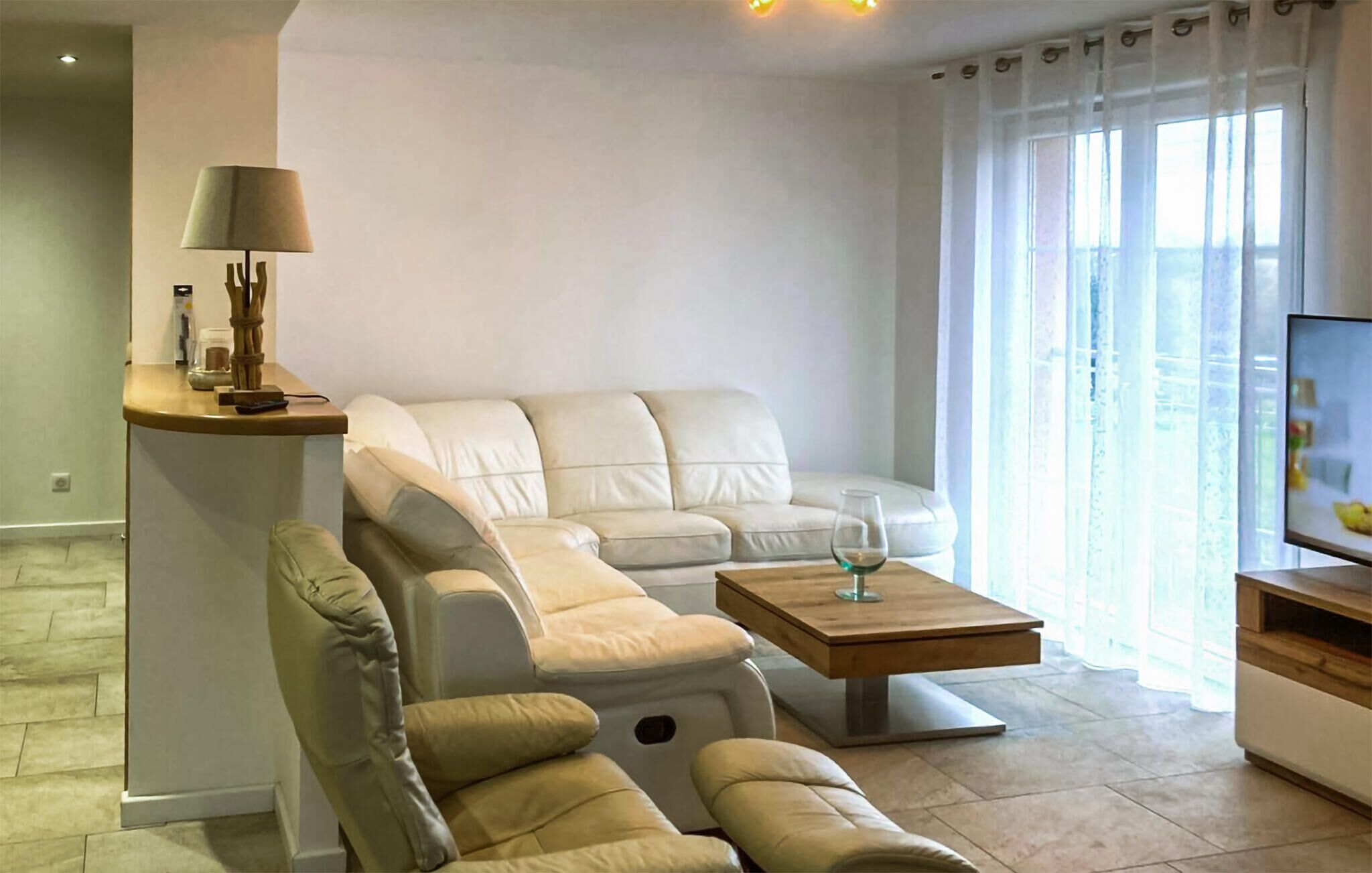 Una sala de estar moderna con un sofá, un sillón reclinable, una mesa de centro y un televisor.