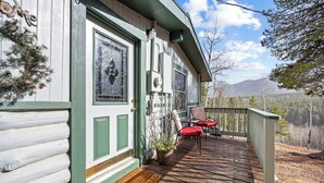 A wooden cabin with a porch, a potted plant, and a red chair.