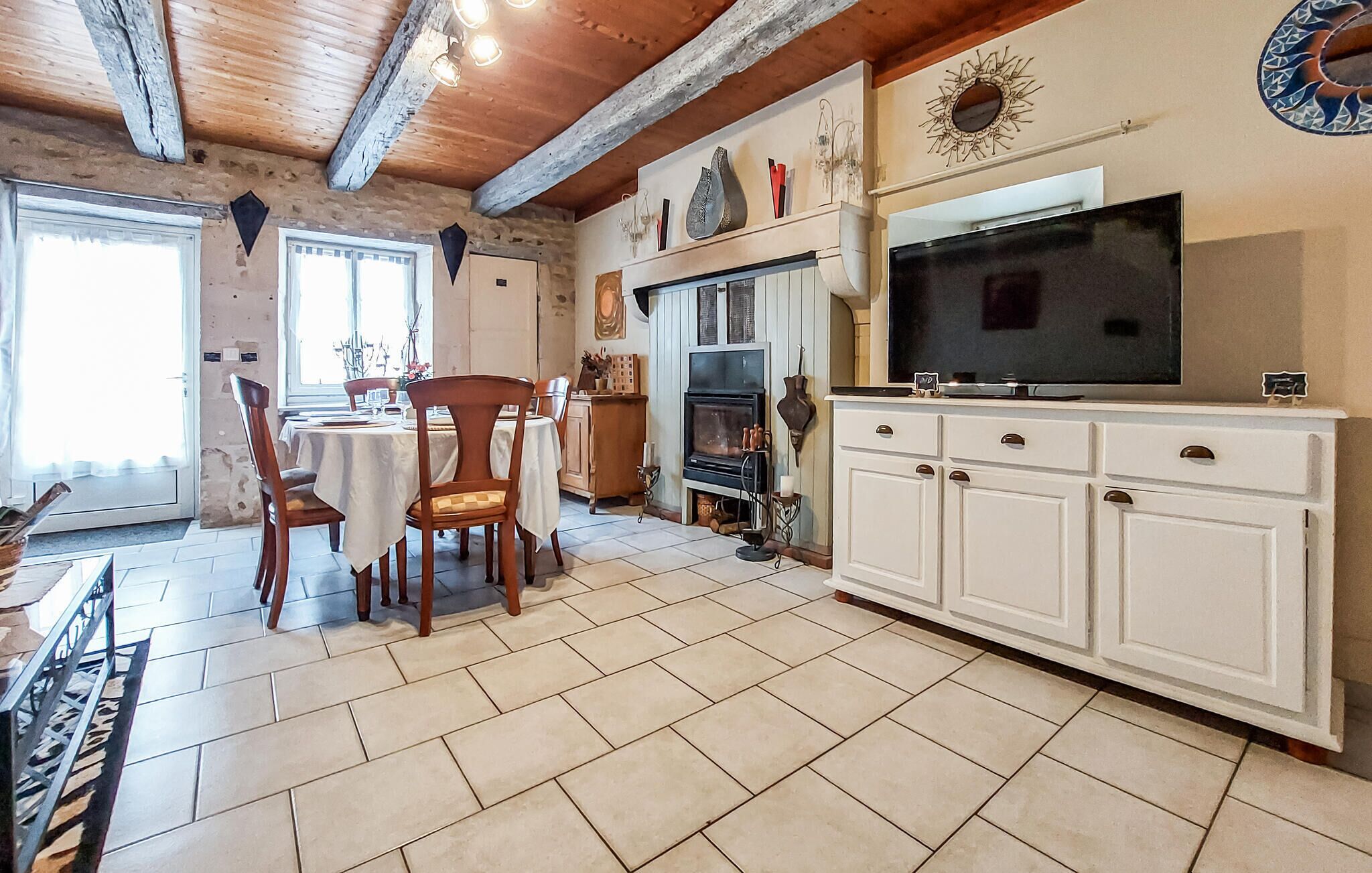 Une pièce comprenant une table à manger, des chaises, un téléviseur, une cheminée et un meuble.