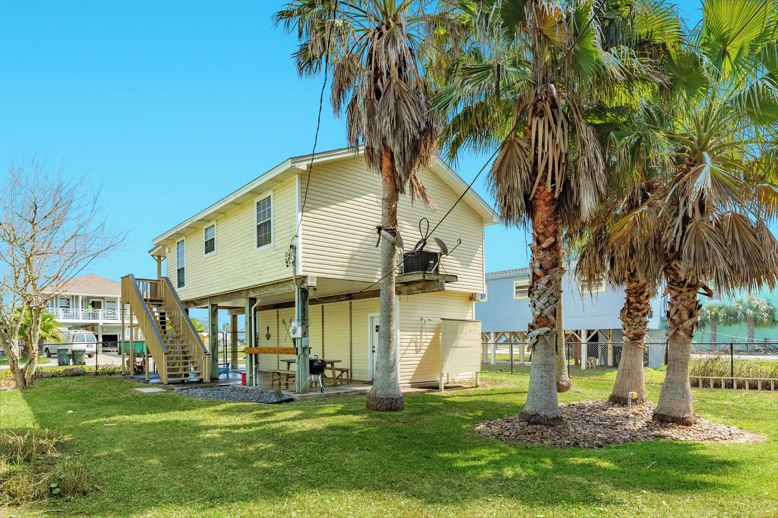 A two-story house with a covered porch, a staircase, and a small outdoor seating area.