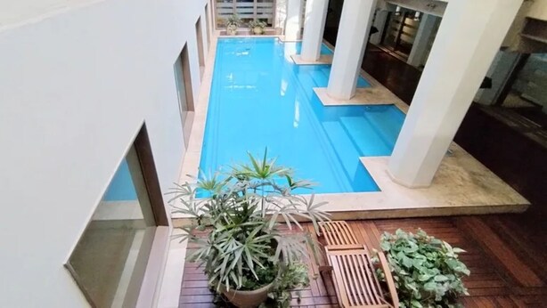 A pool area with a blue pool, white columns, and potted plants. - Puente de la Mujer, your private apartment with the best view in Bs. As. (Buenos Aires)