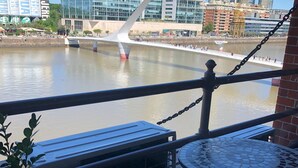A view from a balcony overlooking a river with modern buildings in the background. - Puente de la Mujer, your private apartment with the best view in Bs. As. (Buenos Aires)