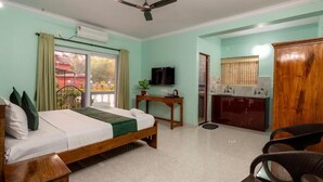 A bedroom with a bed, a desk, a television, a wardrobe, and a ceiling fan. - The Lobos (Benaulim)