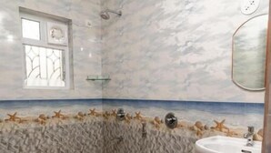 A bathroom with a marble wall design, a toilet, a sink, and a window. - The Lobos (Benaulim)