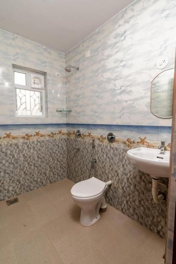 A bathroom with a marble wall design, a toilet, a sink, and a window.