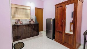 A compact kitchen with a refrigerator, wooden cabinets, and a window with blinds. - The Lobos (Benaulim)