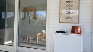 A room with a sliding glass door, a white cabinet with books and a game, and a framed fish illustration on the wall. - A sanctuary by the water – Vejlby Fed (Middelfart)