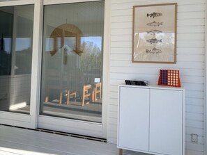 Ein Zimmer mit einer Schiebetür, einem weißen Schrank mit Büchern und einem Spiel sowie einer gerahmten Illustration von Fischen an der Wand.