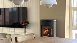 A modern dining area with a TV, fireplace, and two pendant lights. - A sanctuary by the water – Vejlby Fed (Middelfart)