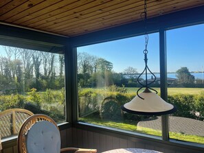 Ein Zimmer mit großem Fenster, einer Pendelleuchte und zwei Korbstühlen.