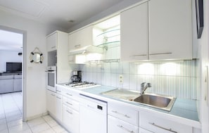 A modern kitchen with white cabinets, a stainless steel sink, and a glass backsplash. - Maison cosy, plage à 600m (Saint-Germain-Sur-Ay)
