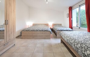 Une chambre avec deux lits, une armoire et une fenêtre avec des rideaux.