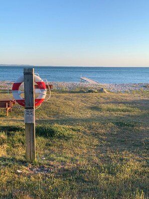 Ein Rettungsring an einem Holzpfosten, eine felsige Küstenlinie und ein hölzerner Steg, der sich ins Wasser erstreckt.