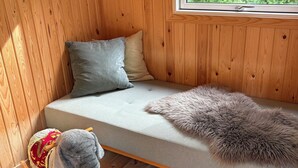 En stuga med träpanel på insidan, inredd med en soffa, kuddar, en mjuk matta och en liten stol.