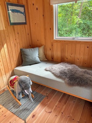 Ein Holzhütten-Innenraum mit einer Couch, Kissen, einem flauschigen Teppich und einem kleinen Sessel.