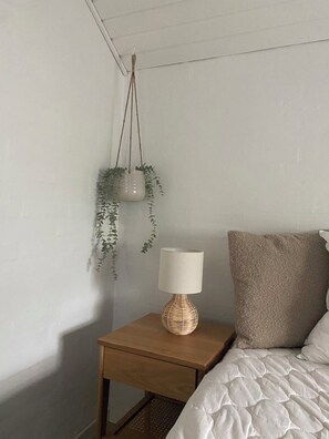 A bedroom with a bed, a bedside table with a lamp, and a hanging plant. - Lovely holiday home 350 meters from Høll Strand (Børkop)