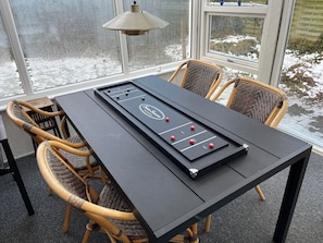 A room with a foosball table, wicker chairs, a table lamp, and a view of the outdoors through large windows. - Lovely holiday home 350 meters from Høll Strand (Børkop)