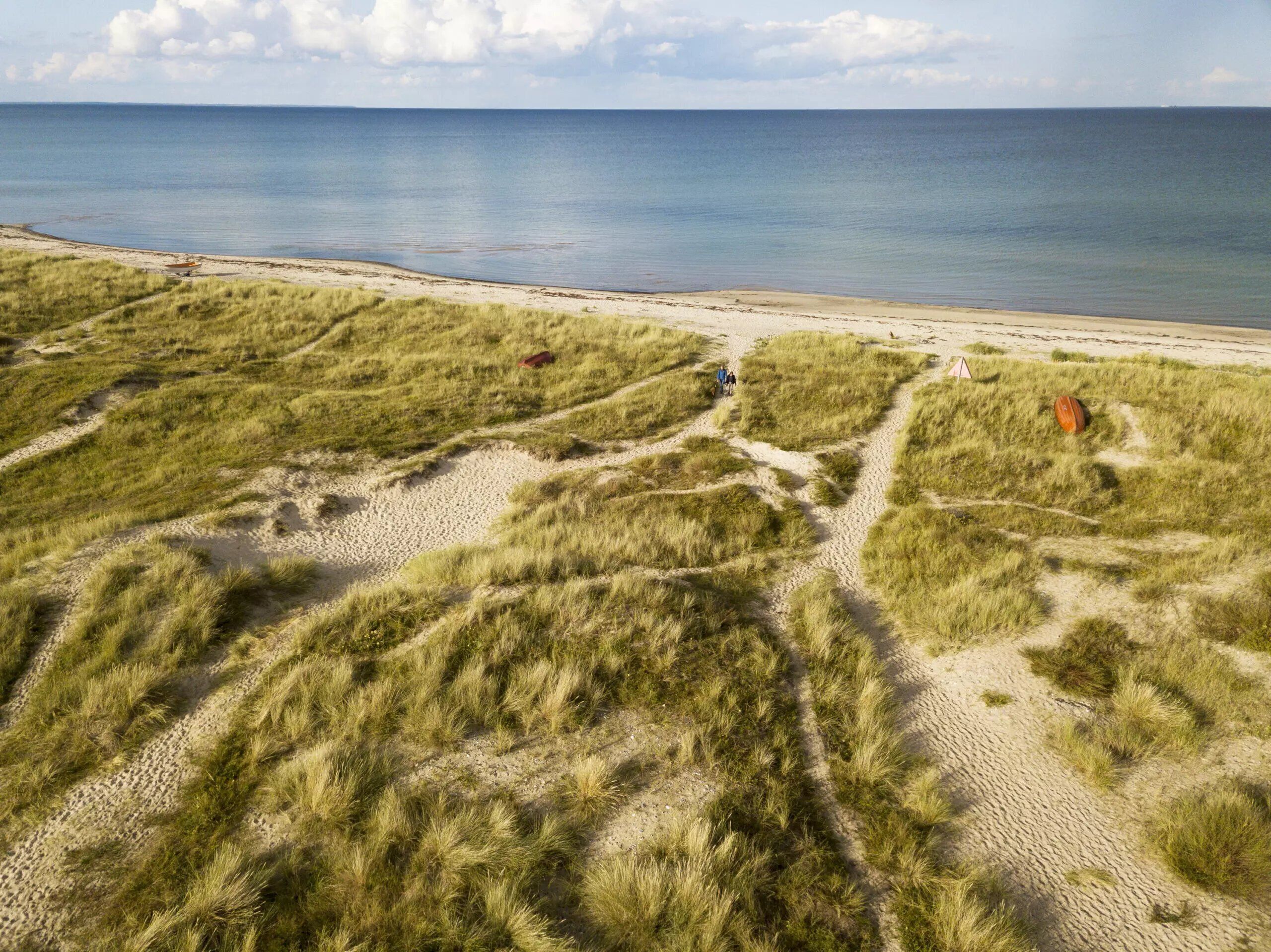 Et kystlandskab med klitter, en strand og frit udsyn til havet.