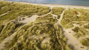 Een kustlandschap met duinen, een strand en helder uitzicht op de zee.