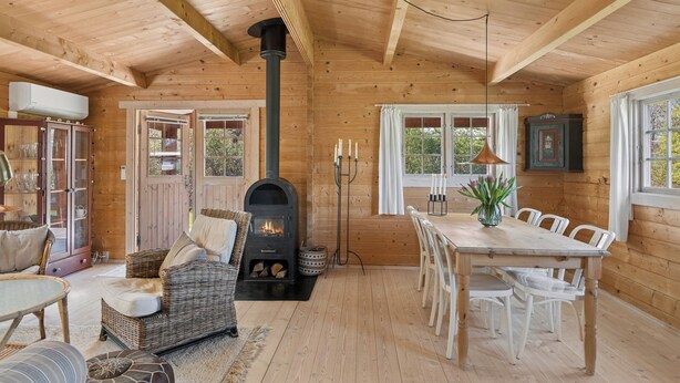 Een houten blokhut interieur met een open haard, een eettafel, stoelen en een gezellige zithoek.