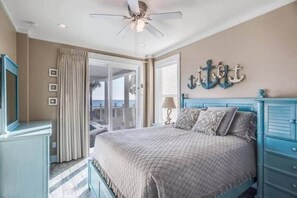 Une chambre à coucher avec un lit, un ventilateur de plafond, une fenêtre avec des rideaux et un élément décoratif mural.
