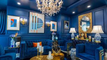 Una habitación con una decoración azul, que incluye un candelabro, sofás, una mesa de centro y elementos decorativos.