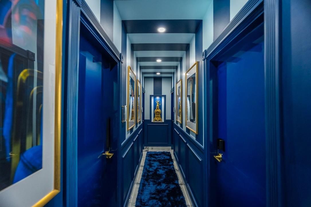 A hallway with blue walls, framed pictures, and a carpeted floor.