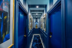 A hallway with blue walls, framed pictures, and a carpeted floor.