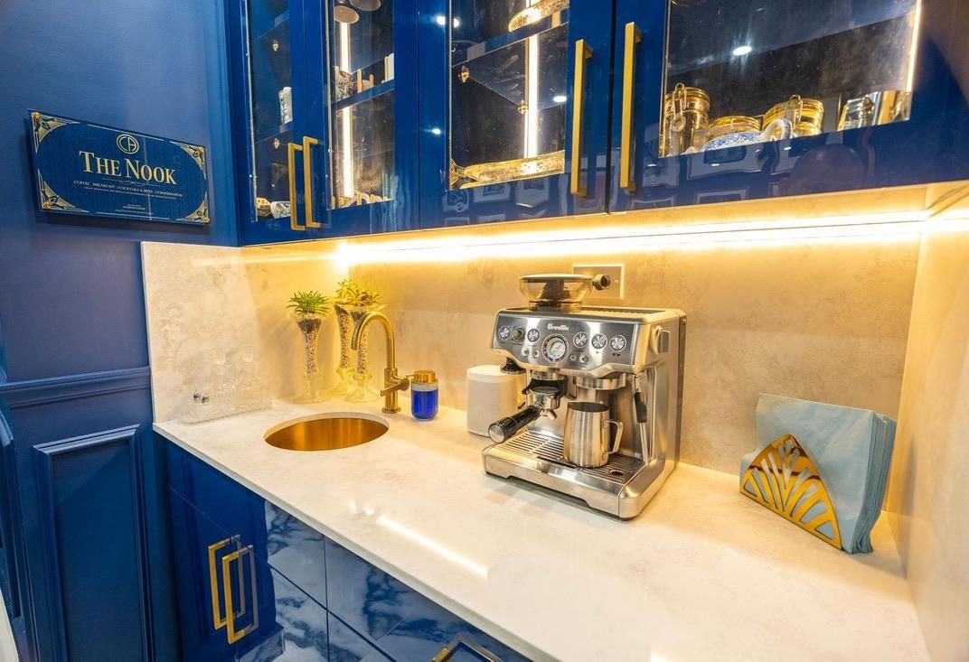 A kitchen with a coffee machine, a sink, and blue cabinets.