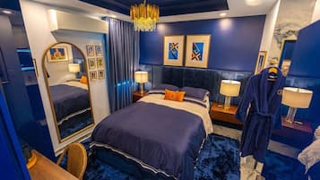 Una habitación de hotel con una cama grande, lámparas de noche, un espejo y obras de arte en las paredes.