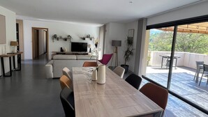 A modern living room with a dining area, a TV, and a balcony with outdoor furniture. - NEW VILLA WITH POOL, WIFI, NEAR ILE ROUSSE (VILLE DI PARASO)