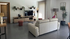 A modern living room with a sofa, TV, and decorative plants. - NEW VILLA WITH POOL, WIFI, NEAR ILE ROUSSE (VILLE DI PARASO)