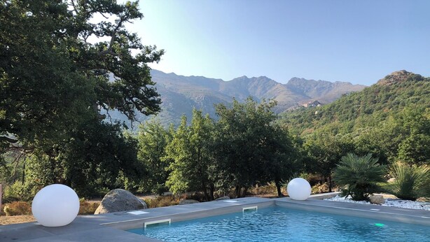 A pool with a mountain backdrop, surrounded by trees and rocks. - NEW VILLA WITH POOL, WIFI, NEAR ILE ROUSSE (VILLE DI PARASO)