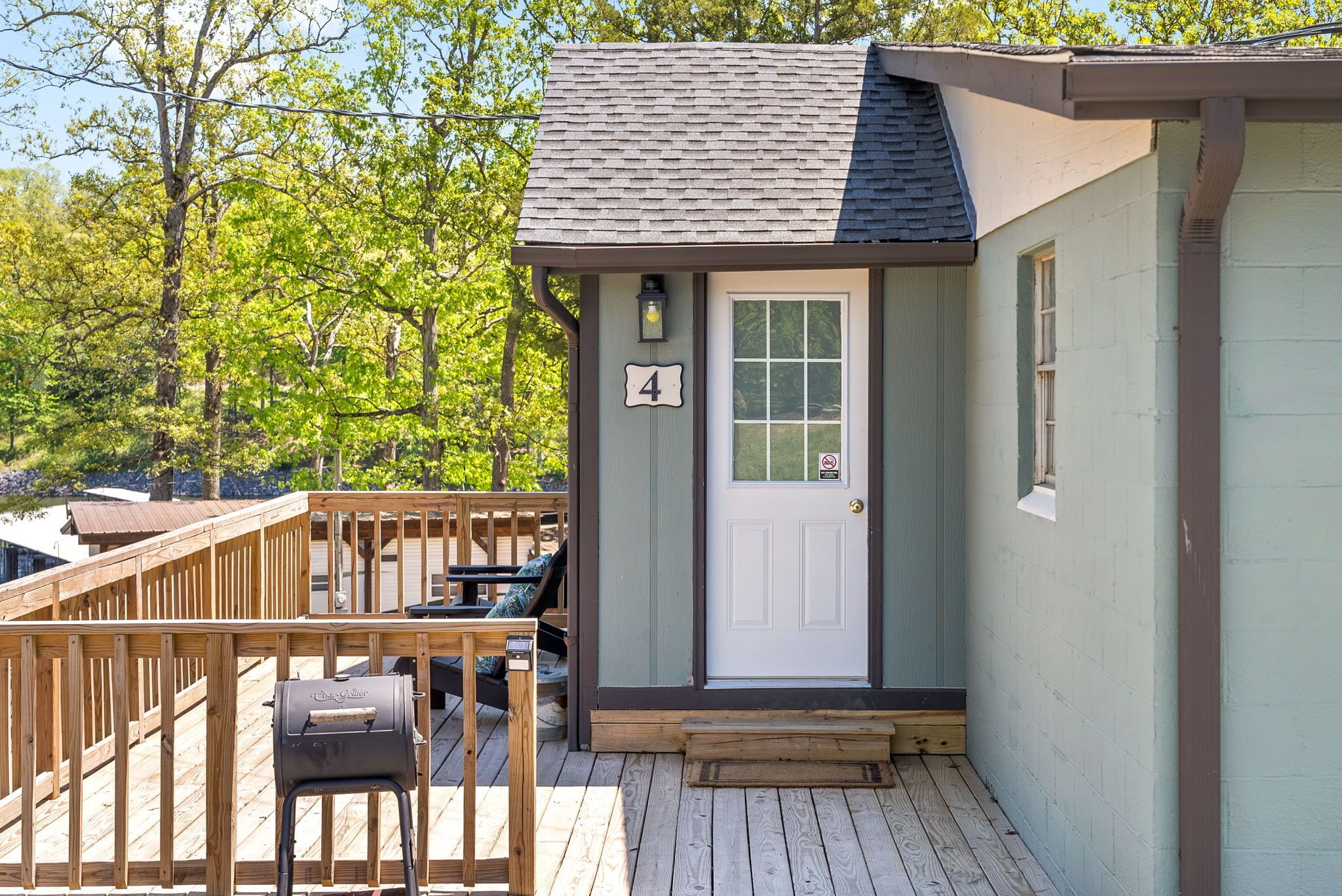 Une petite cabane dotée d’une terrasse en bois, d’un barbecue et d’une porte portant le numéro 4.