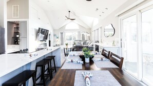 Une cuisine moderne dotée d’un grand îlot central, de tabourets de bar et d’un coin repas avec une table dressée pour quatre personnes.