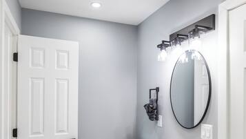 A bathroom with a white toilet, a dark vanity with a mirror, and a white sink.