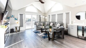 Un salon spacieux avec un canapé gris, deux tables basses et un ventilateur de plafond.