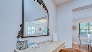 A modern bathroom with a wooden vanity, a large mirror, and a chair. - Terracotta Tides • 175 Steps to Indian Rocks Beach • Sleeps 6 • Sunrise & Sunset (Indian Rocks Beach)