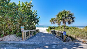 A beach pathway leading to the ocean, surrounded by greenery and palm trees. - Terracotta Tides • 175 Steps to Indian Rocks Beach • Sleeps 6 • Sunrise & Sunset (Indian Rocks Beach)