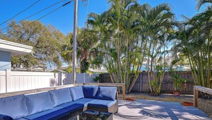A wooden deck with a blue outdoor sofa and a small table. - Terracotta Tides • 175 Steps to Indian Rocks Beach • Sleeps 6 • Sunrise & Sunset (Indian Rocks Beach)