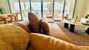 Ein modernes Wohnzimmer mit einem großen Schiebeglasfenster, das auf eine Terrasse im Freien führt.
