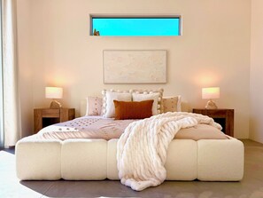 Ein Schlafzimmer mit einem großen Bett, zwei Nachttischen, einem Fenster und einem Wandbild.