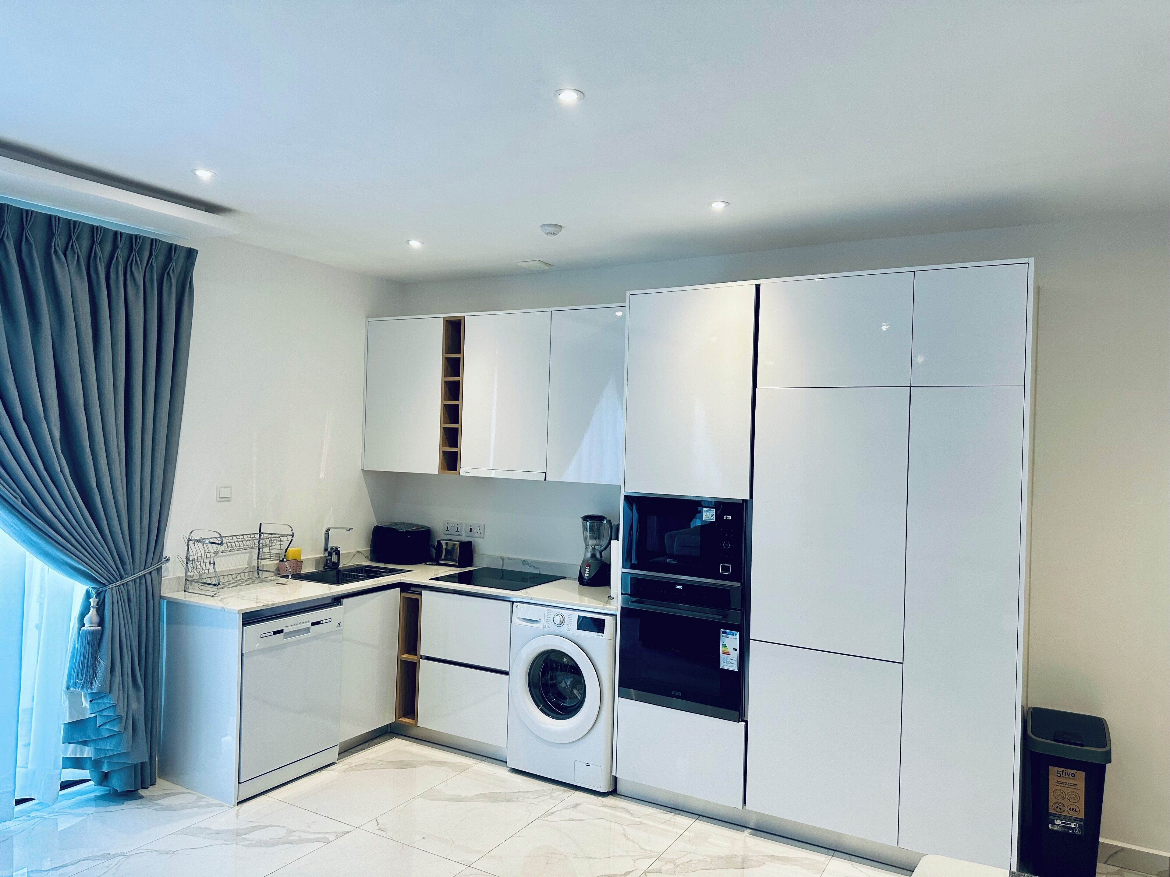 A modern kitchen with built-in appliances, including a dishwasher, washing machine, and microwave.