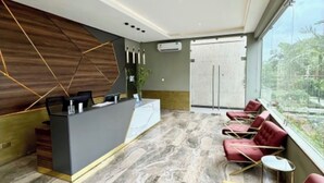 Ein moderner Empfangsbereich mit Marmorboden, einer Rezeption und roten Sitzgelegenheiten am Fenster.