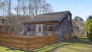 A two-story wooden cabin with a fenced backyard, a deck, and a garage. - Coastal Escape with Fireplace, Three Decks & Easy Beach Access (Cannon Beach)