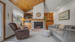 A cozy living room with a fireplace, a comfortable sofa, a recliner, and a wooden ceiling. - Coastal Escape with Fireplace, Three Decks & Easy Beach Access (Cannon Beach)