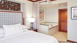 Ein Hotelzimmer mit einem großen Bett, einem Nachttisch mit Lampe, einem Badezimmer mit Waschbecken und Dusche sowie einer Holztür.